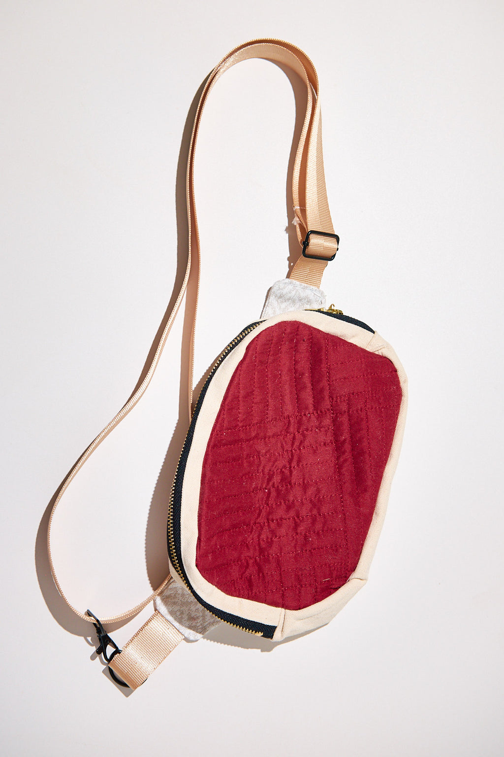 Fanny pack with red center design and white border and a beige strap upcycled from a comforter on a white background