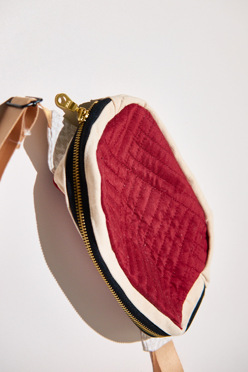 Red and beige fanny pack upcycled from a comforter with a gold zipper on a white background