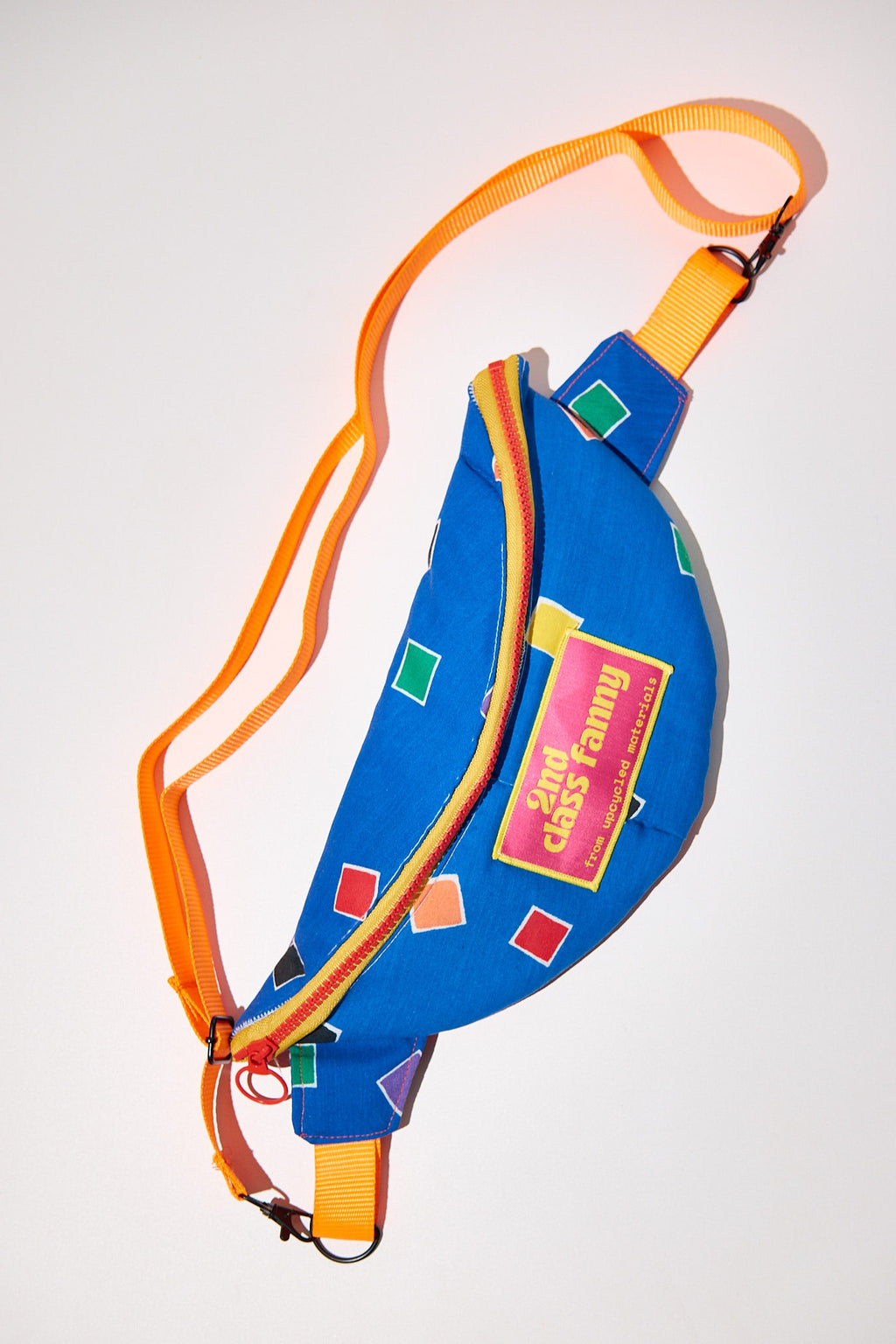 Colorful bag with an orange strap upcycled from comforter on a white background