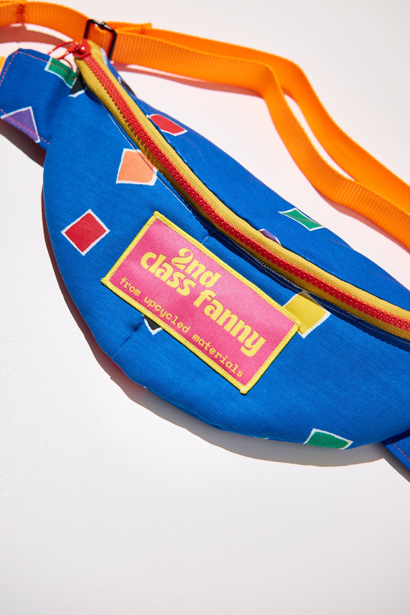 Colorful fanny pack with geometric patterns and a label upcycled from comforter on a white background