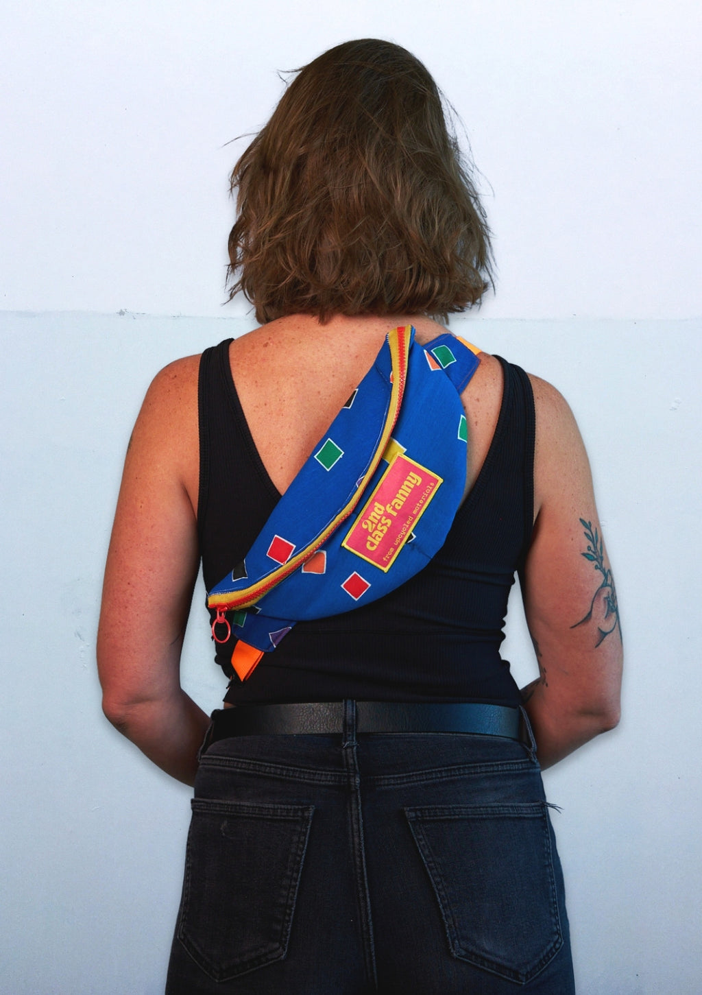 Person wearing a colorful bag over one shoulder upcycled from comforter against a light blue background
