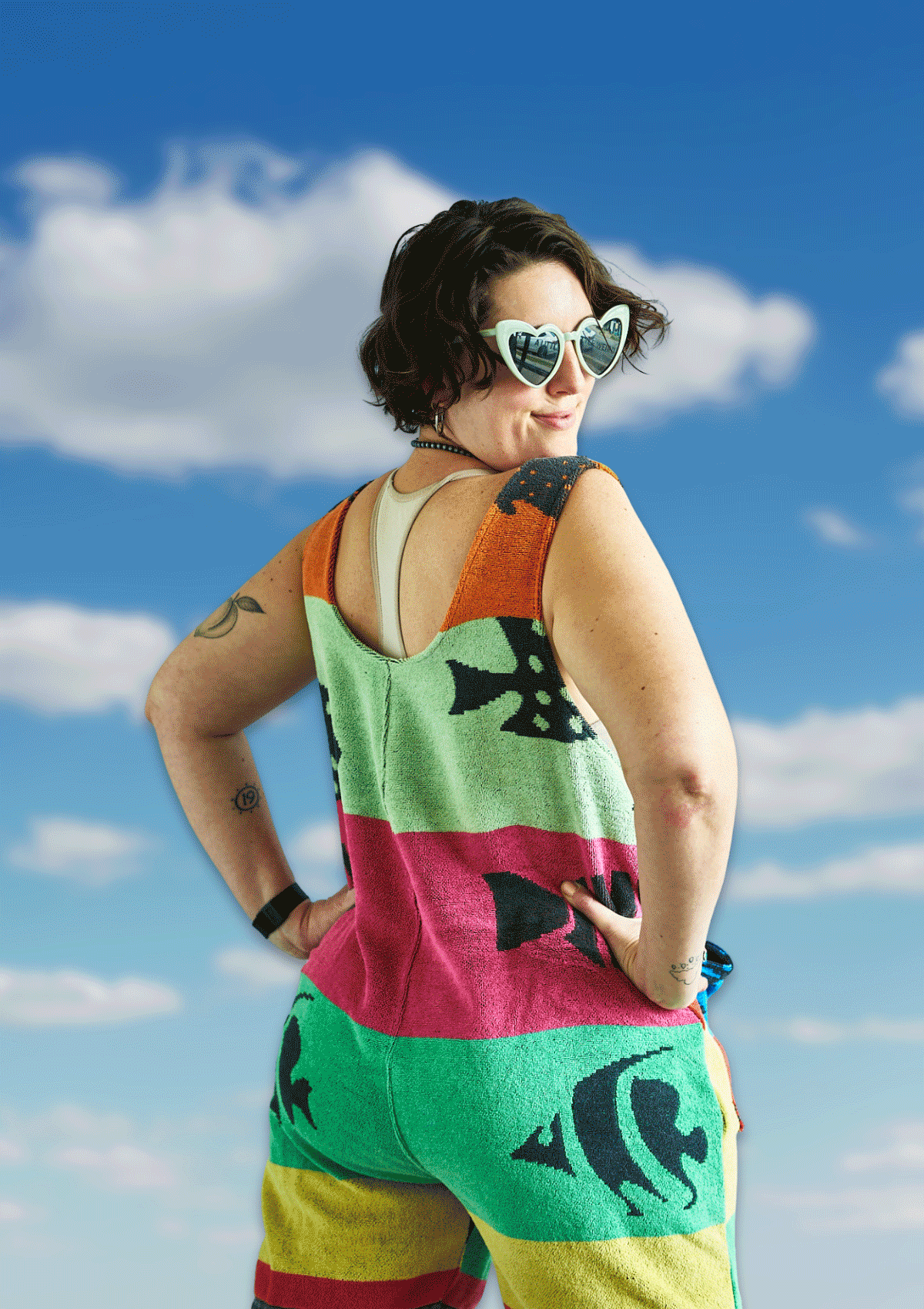 Person wearing a colorful romper / jumper with stripes upcycled from a beach towel against a blue sky.