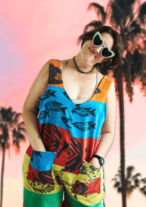 Person wearing a colorful sleeveless romper upcycled from a beach towel with a palm tree background