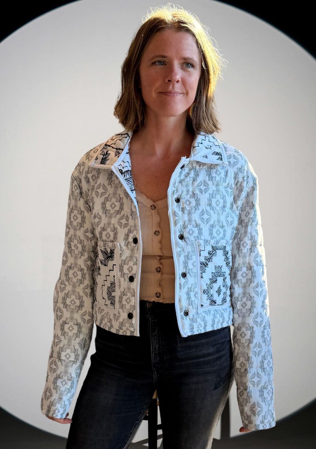 Woman wearing a black and white patterned jacket upcycled from a comforter with a plain background