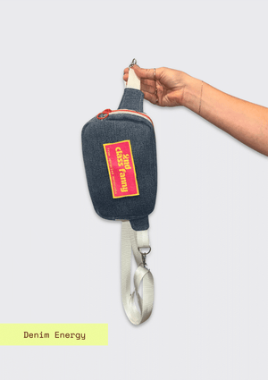 Hand holding Denim fanny pack / cross body bag with label reads 2nd Class Fanny on a gray background
