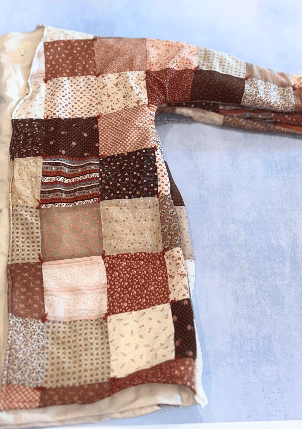 Patchwork quilt with brown and beige patterns on a light blue background