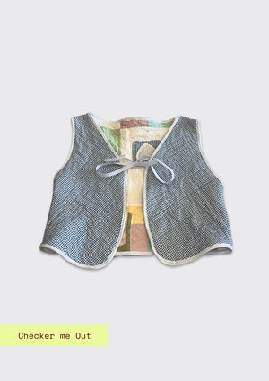 Textured vest with a bow upcycled from a quilt on a light gray background