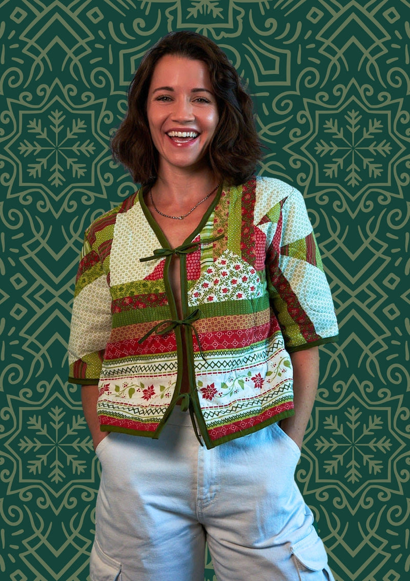 Woman wearing a colorful patterned holiday jacket upcycled from comforter against a green patterned background