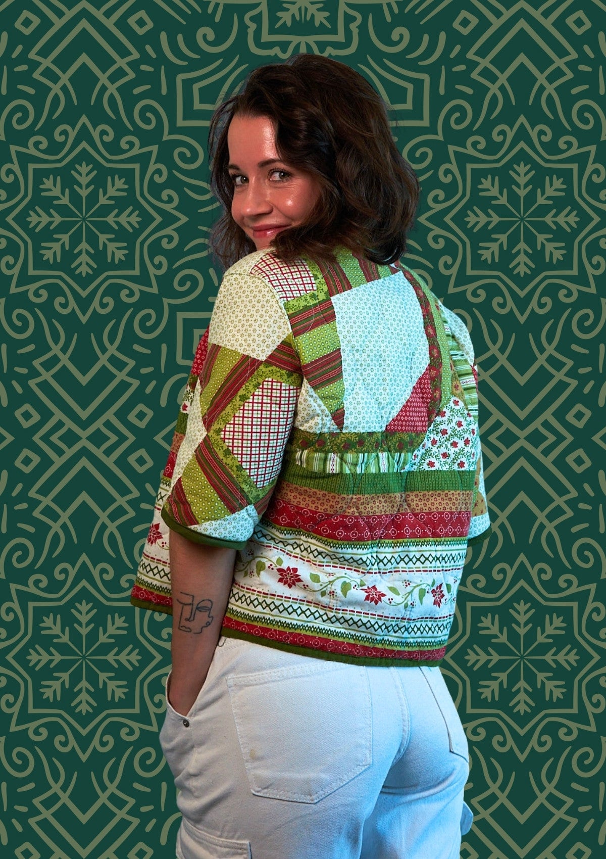 Woman wearing a colorful patterned top  upcycled from comforter against a green geometric-patterned wall.