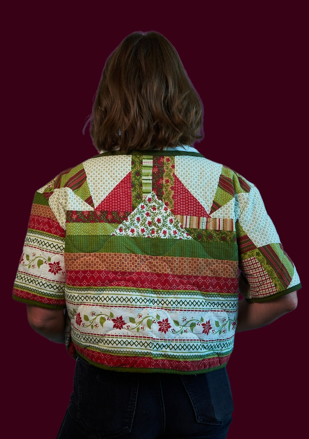 Person wearing a colorful holiday patchwork shirt with a festive patterned design upcycled from a comforter on a dark background