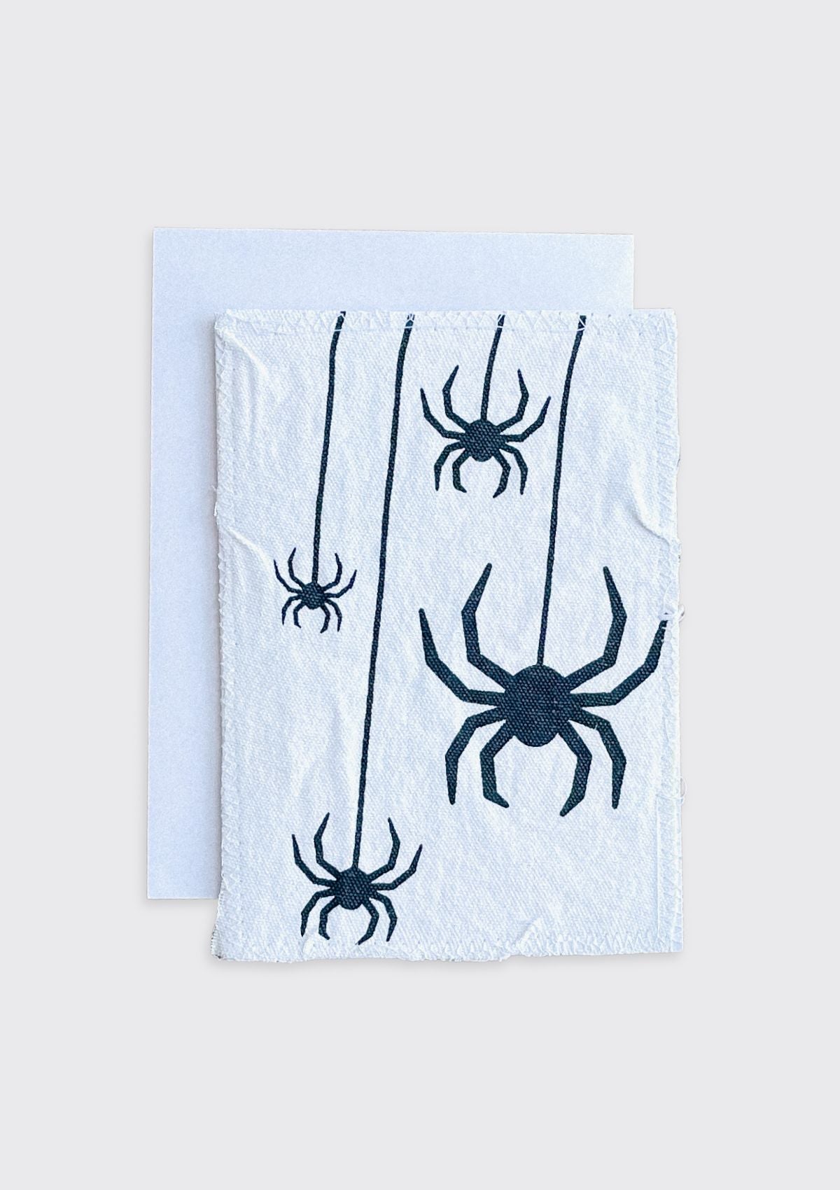 White towel with black spider designs on a greeting card with a light cream background