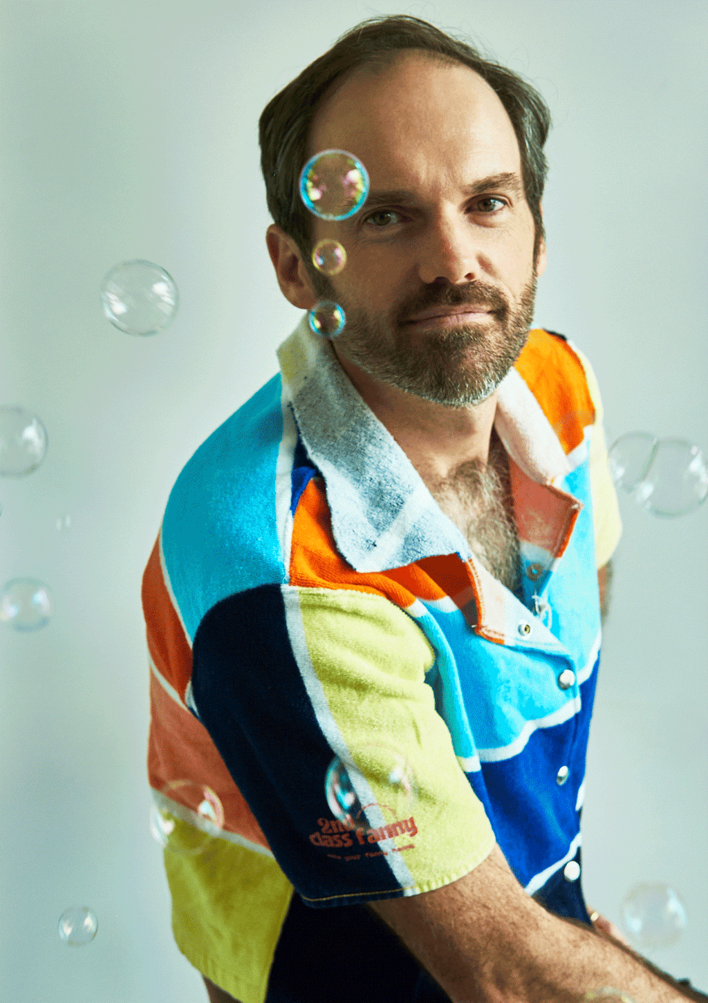 Man wearing a colorful button up shirt upcycled from a beach towel with soap bubbles in the background