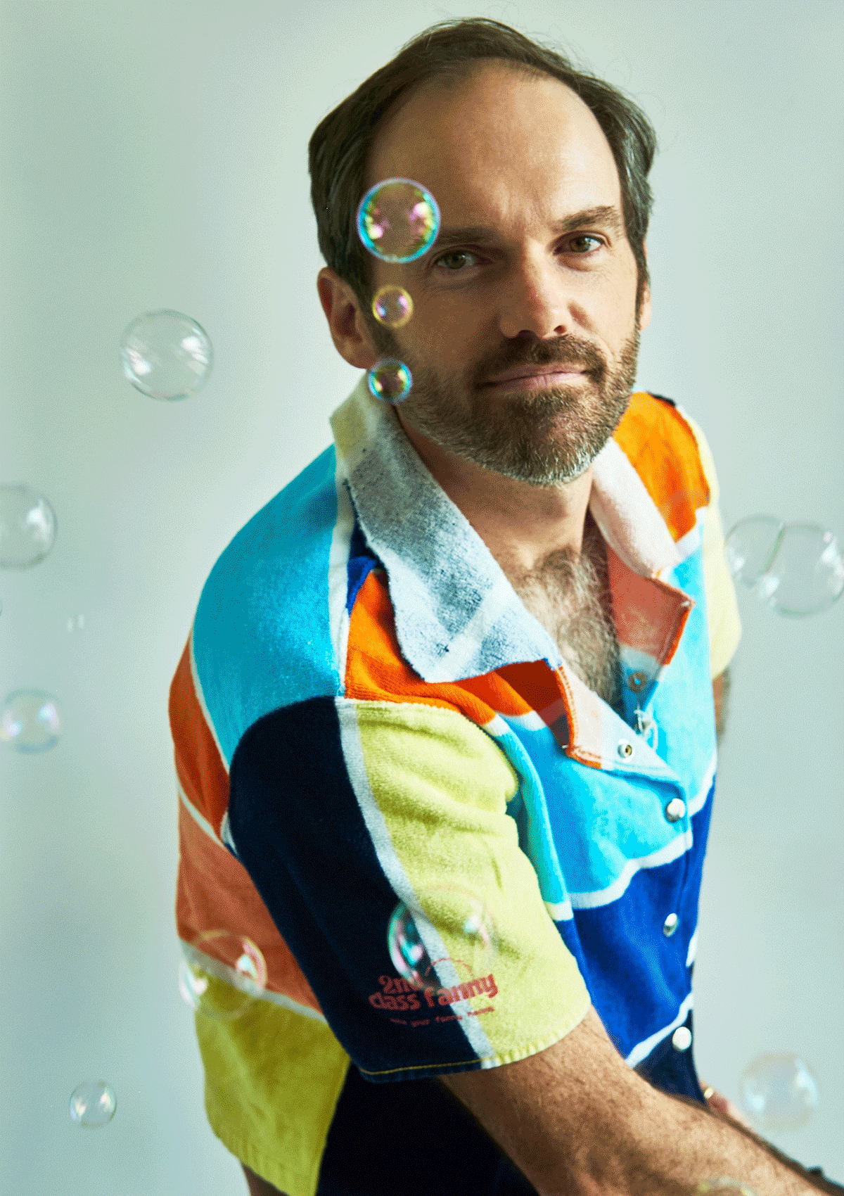 Man wearing a colorful button up shirt upcycled from a beach towel with soap bubbles in the background