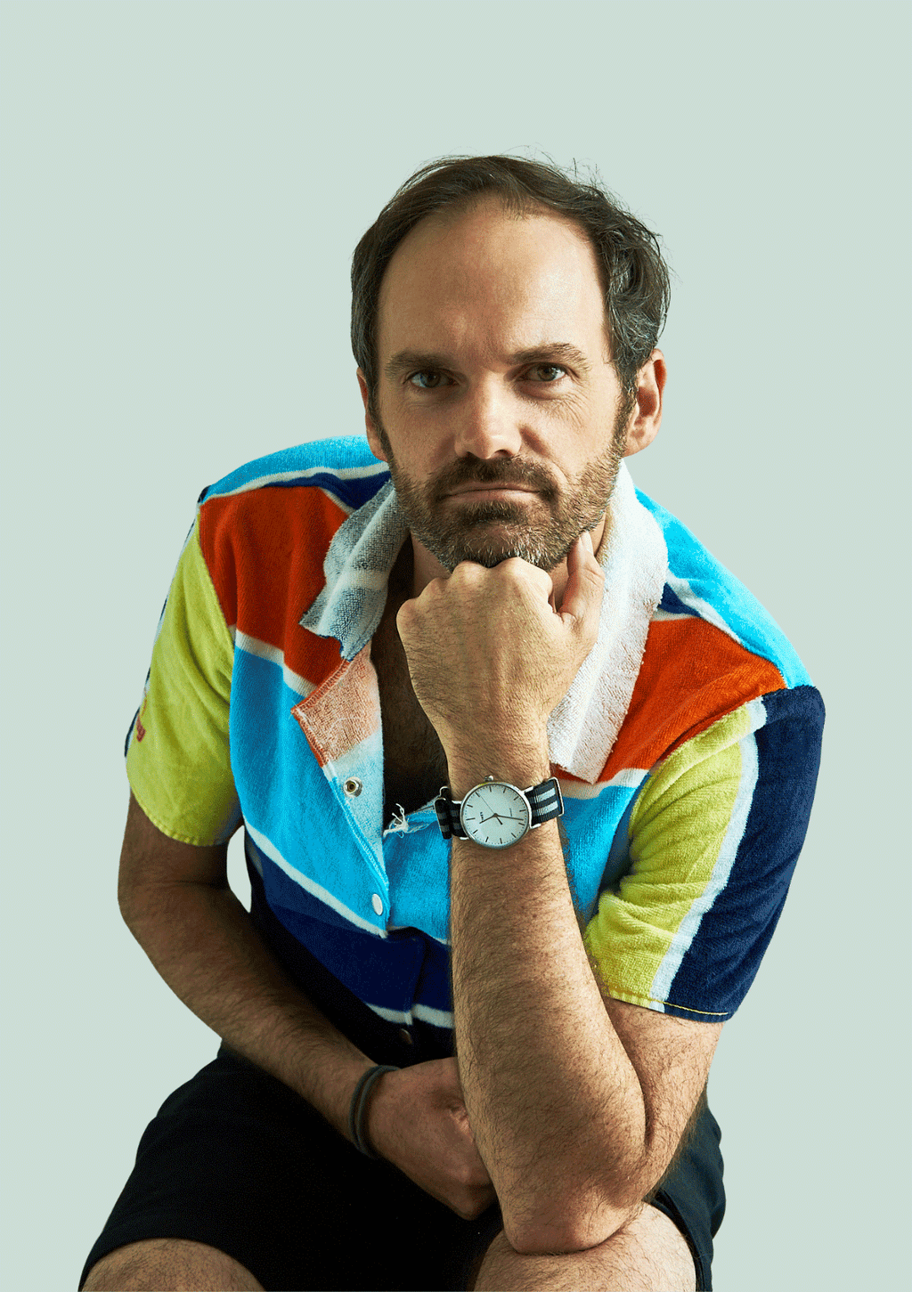 Man wearing a colorful shirt upcycled from a beach towel, sitting against a light gray background