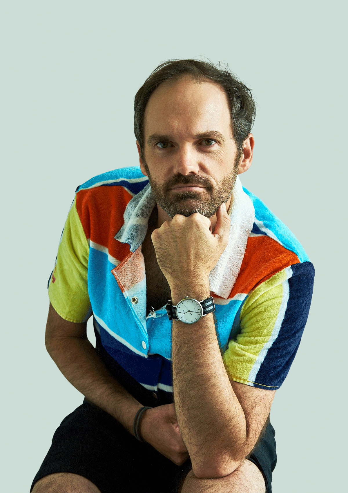 Man wearing a colorful shirt upcycled from a beach towel, sitting against a light gray background