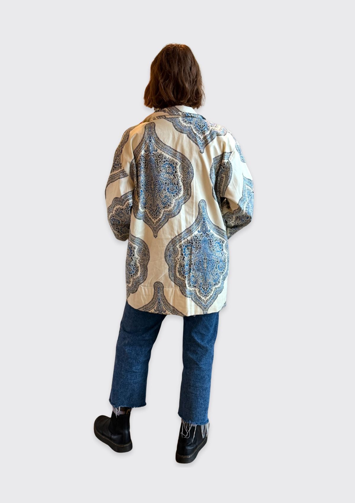 Person wearing a patterned jacket upcycled from a curtain on a white background