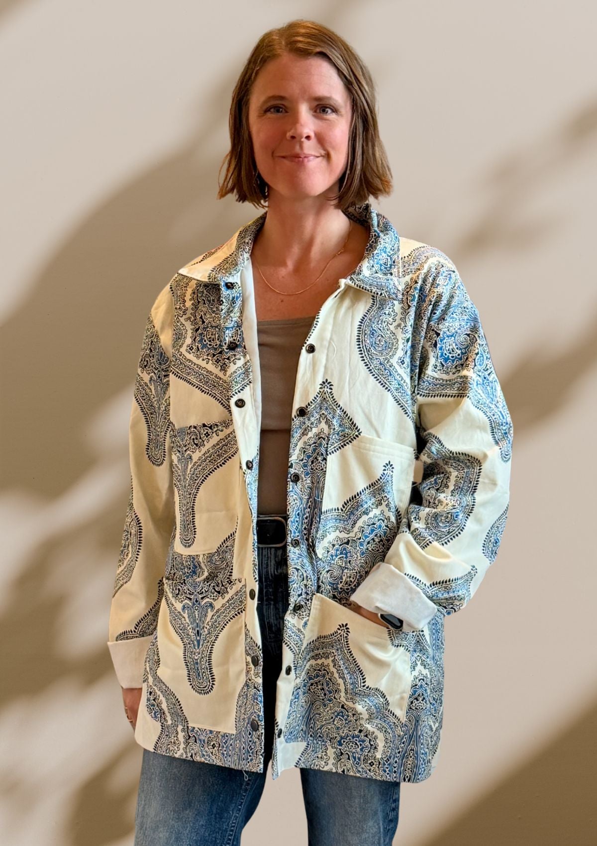 Woman wearing a patterned jacket upcycled from a curtain against a neutral background