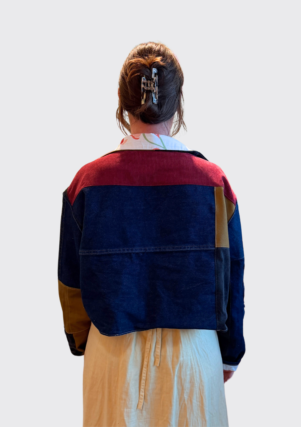 Person wearing a colorful jacket upcycled from pants with a plain background