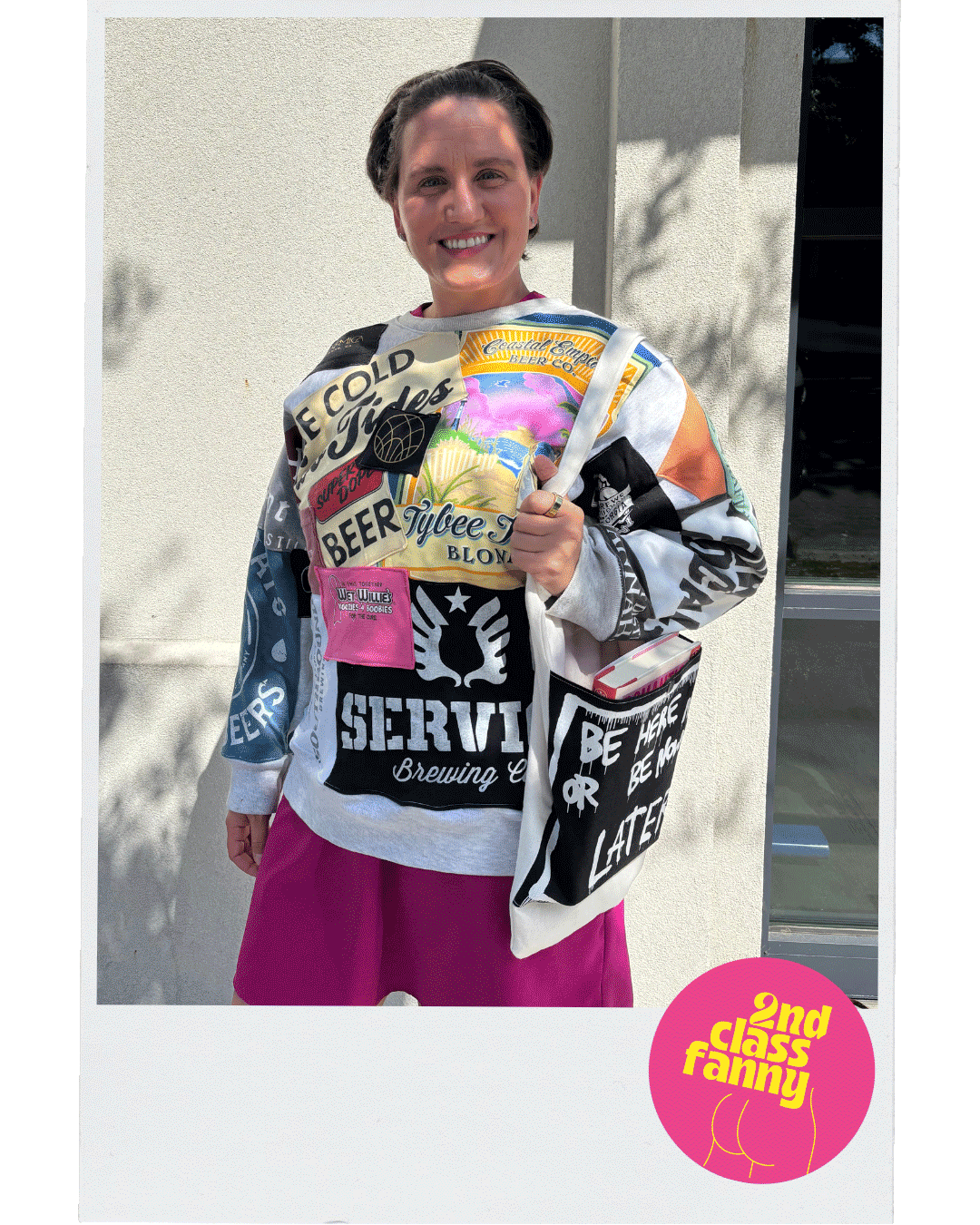 Person wearing a colorful graphic sweatshirt with text and logos, holding a similar sweatshirt.