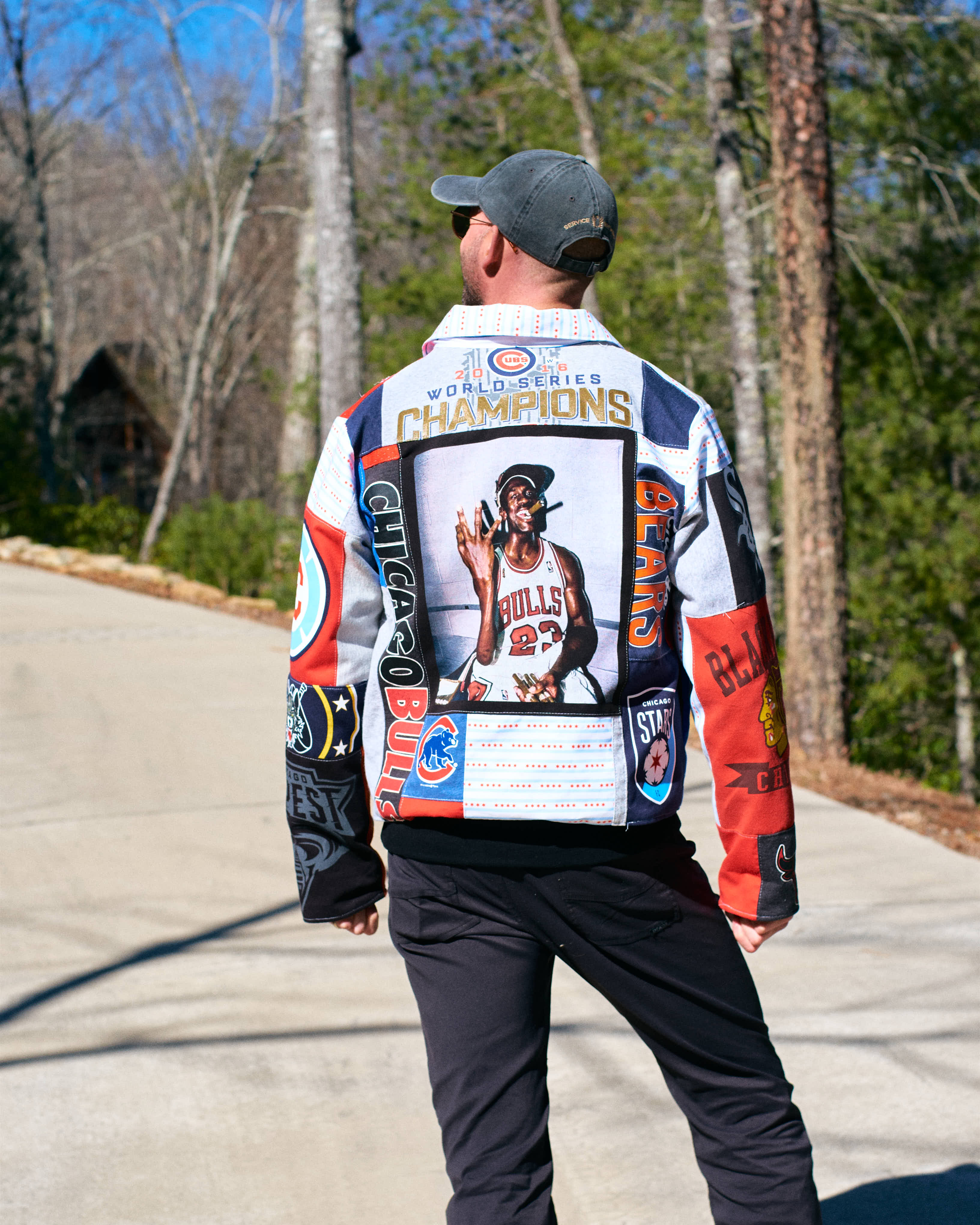 Person wearing a colorful jacket upcycled from sports shirts with sports-themed designs outdoors.