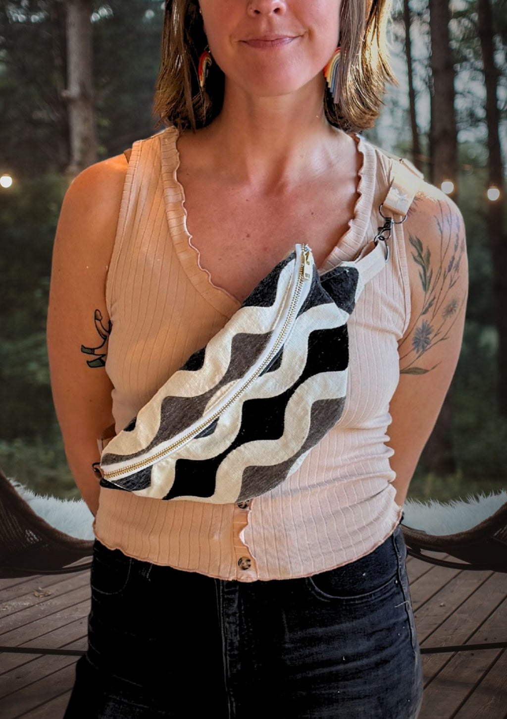 Woman wearing a beige sleeveless top with a black and white patterned pouch over her shoulder, upcycled from designer deadstock fabric standing in a forest setting.