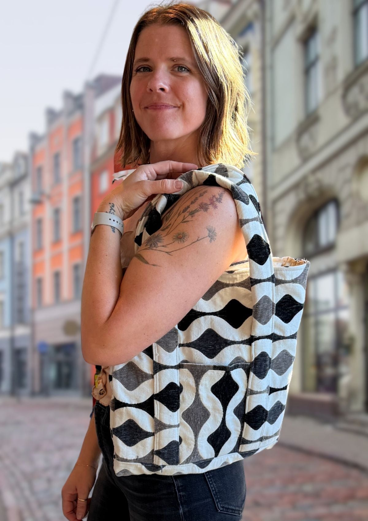 Woman holding a patterned bag upcycled from designer deadstock fabric on a city street
