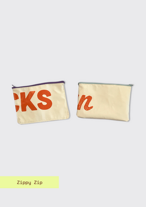 Two white pouches upcycled from an Earth Day billboard with text on a light gray background