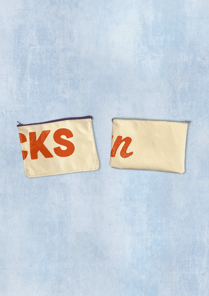 Two white pouches with text on a denim background