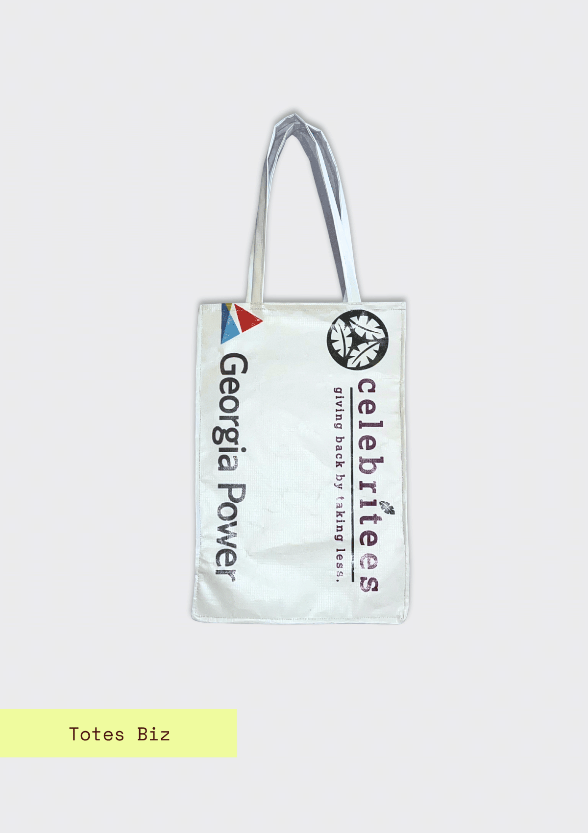 Tote bag with logos from Georgia Power and Celebritees giving back by taking less pattern, upcycled from an Earth Day Banner on a light blue textured background with Totes Biz branding.