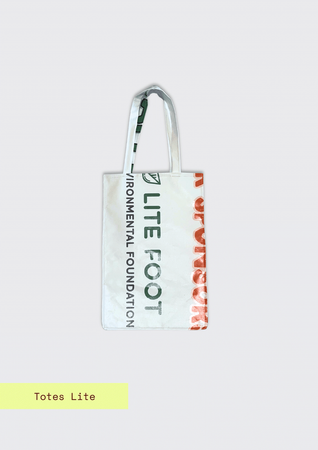 Tote bag with partial words, Lite Foot Foundation pattern, upcycled from an Earth Day Banner on a light blue textured background with Totes Lite branding.