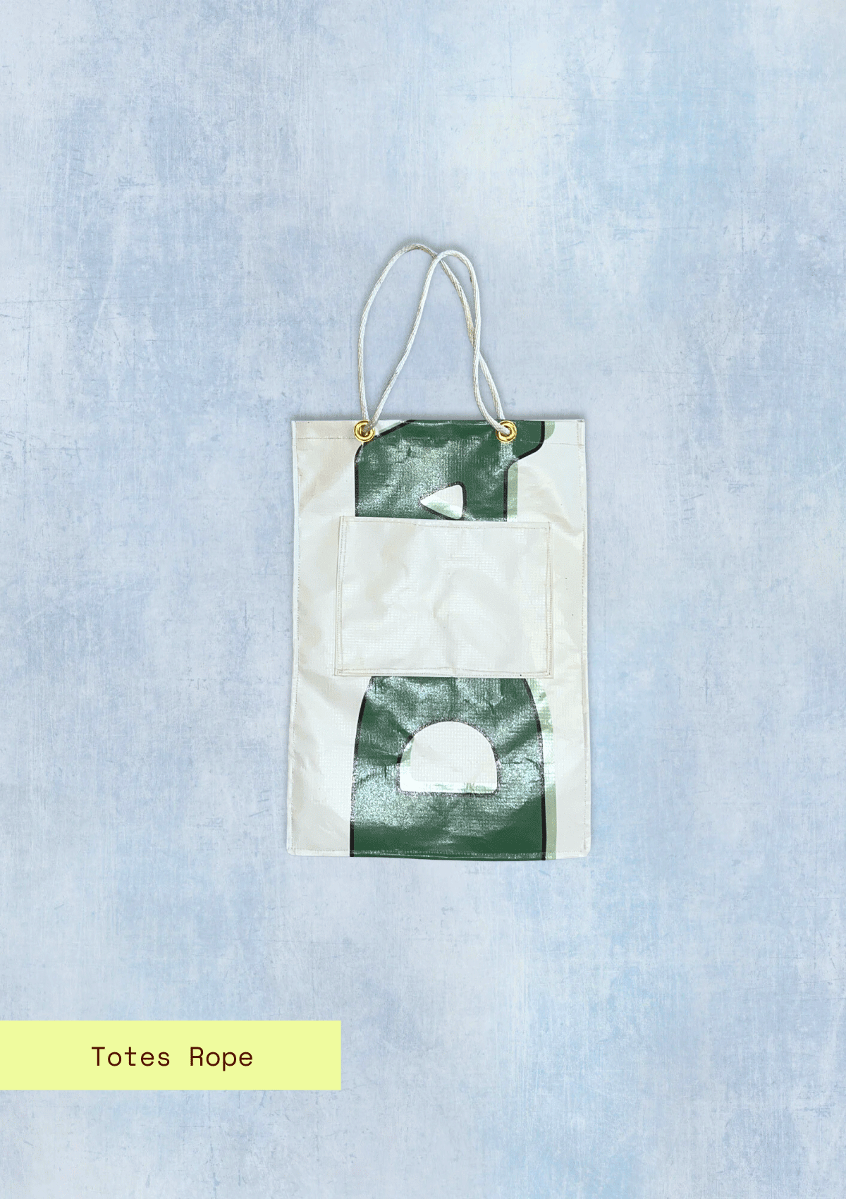 Tote bag with letters pattern and rope handles, upcycled from an Earth Day Banner on a light blue textured background with totes Rope branding.
