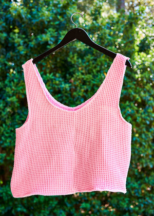 Pink checkered tank top from upycycled towel on a hanger against a green leafy background