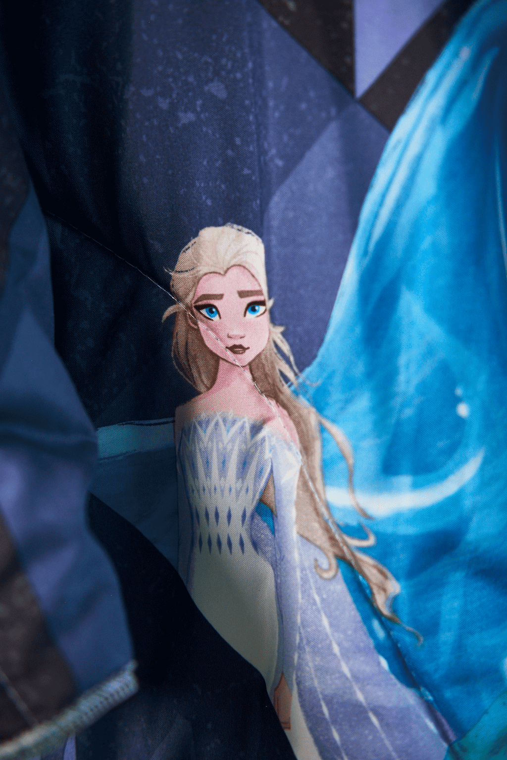 Close up details of Frozen character in a snowy landscape on a jacket upcycled from a Frozen theme sleeping bag with blue and white tones