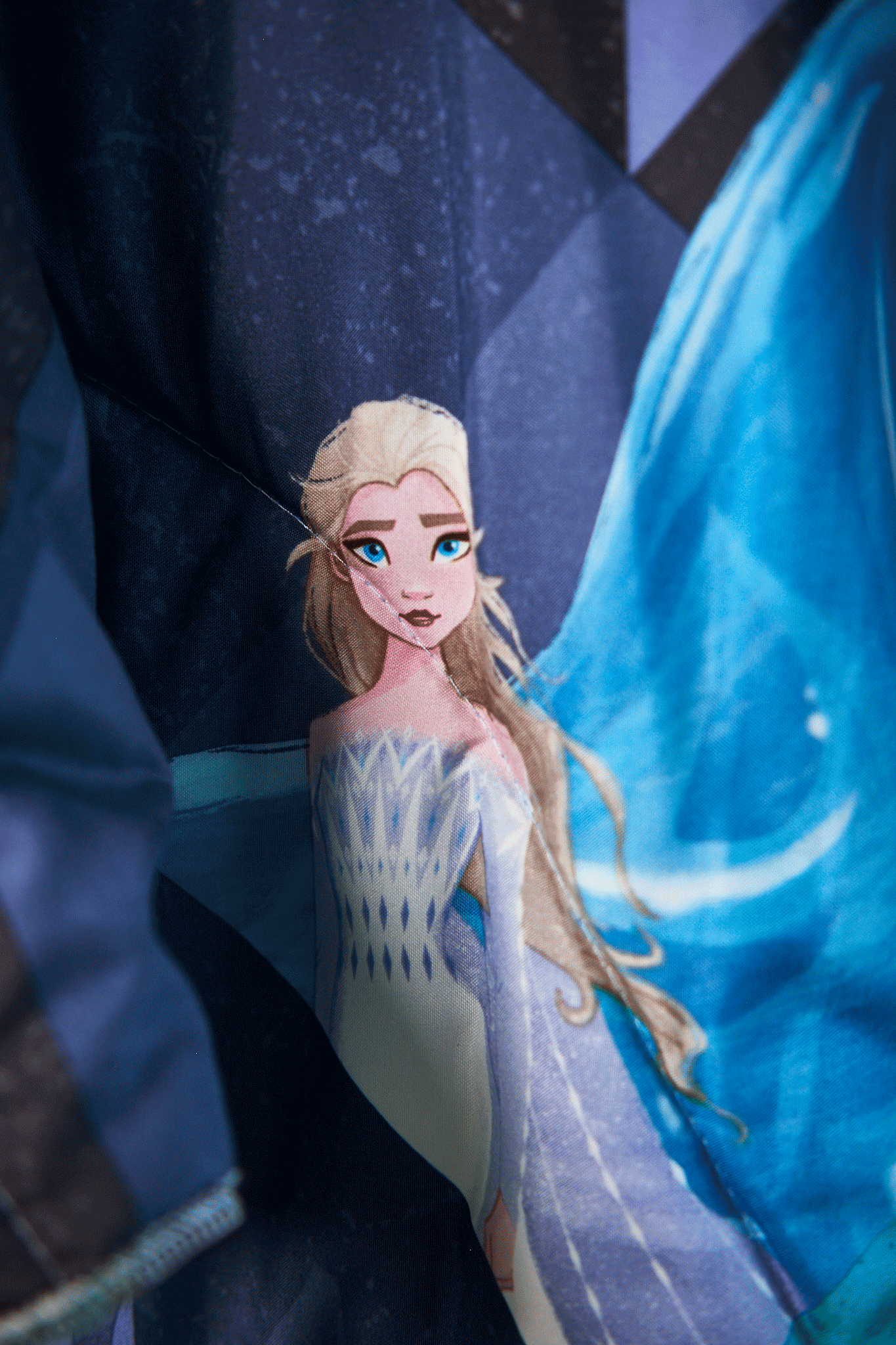 Close up details of Frozen character in a snowy landscape on a jacket upcycled from a Frozen theme sleeping bag with blue and white tones