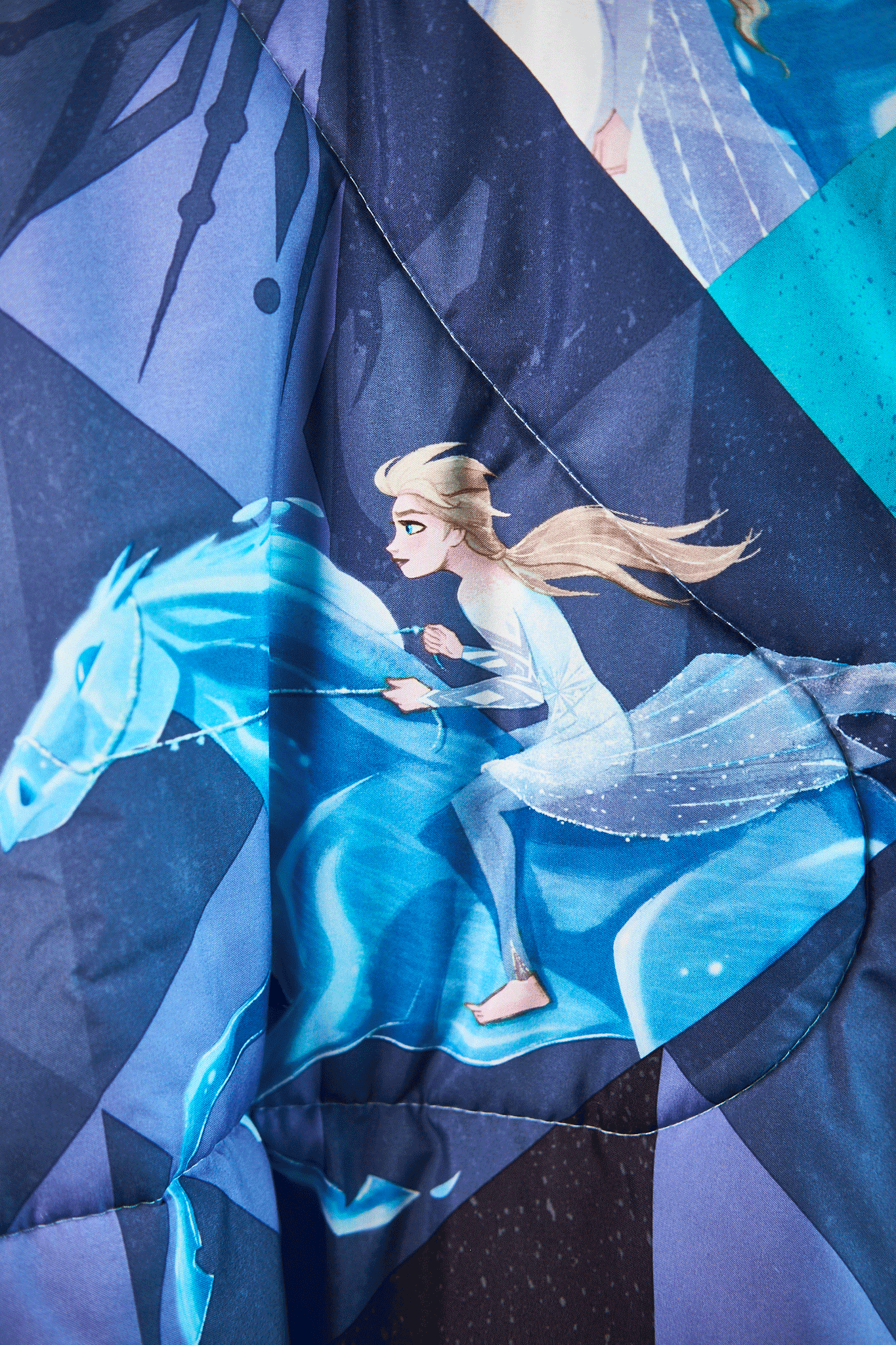 Detail of Frozen character riding a horse with a blue and white color scheme on a dark background upcycled from a sleeping bag.
