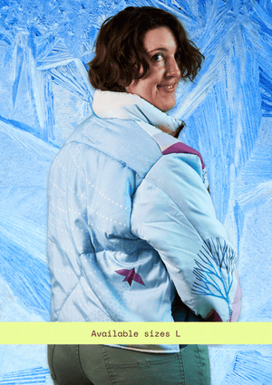 Person wearing an upcycled light blue Frozen winter jacket design against a frosty window background.