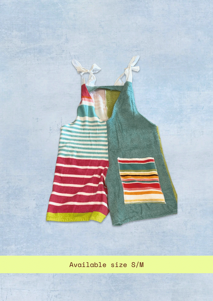 A romper made from an upcycled colorful stripe beach towel on a textured denim background.