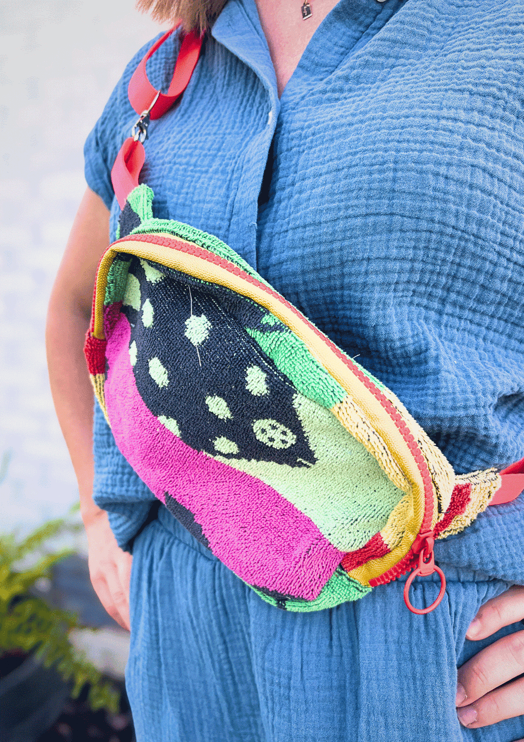 Person wearing a colorful cross body bag upcycled from beach towel, wearing a blue shirt