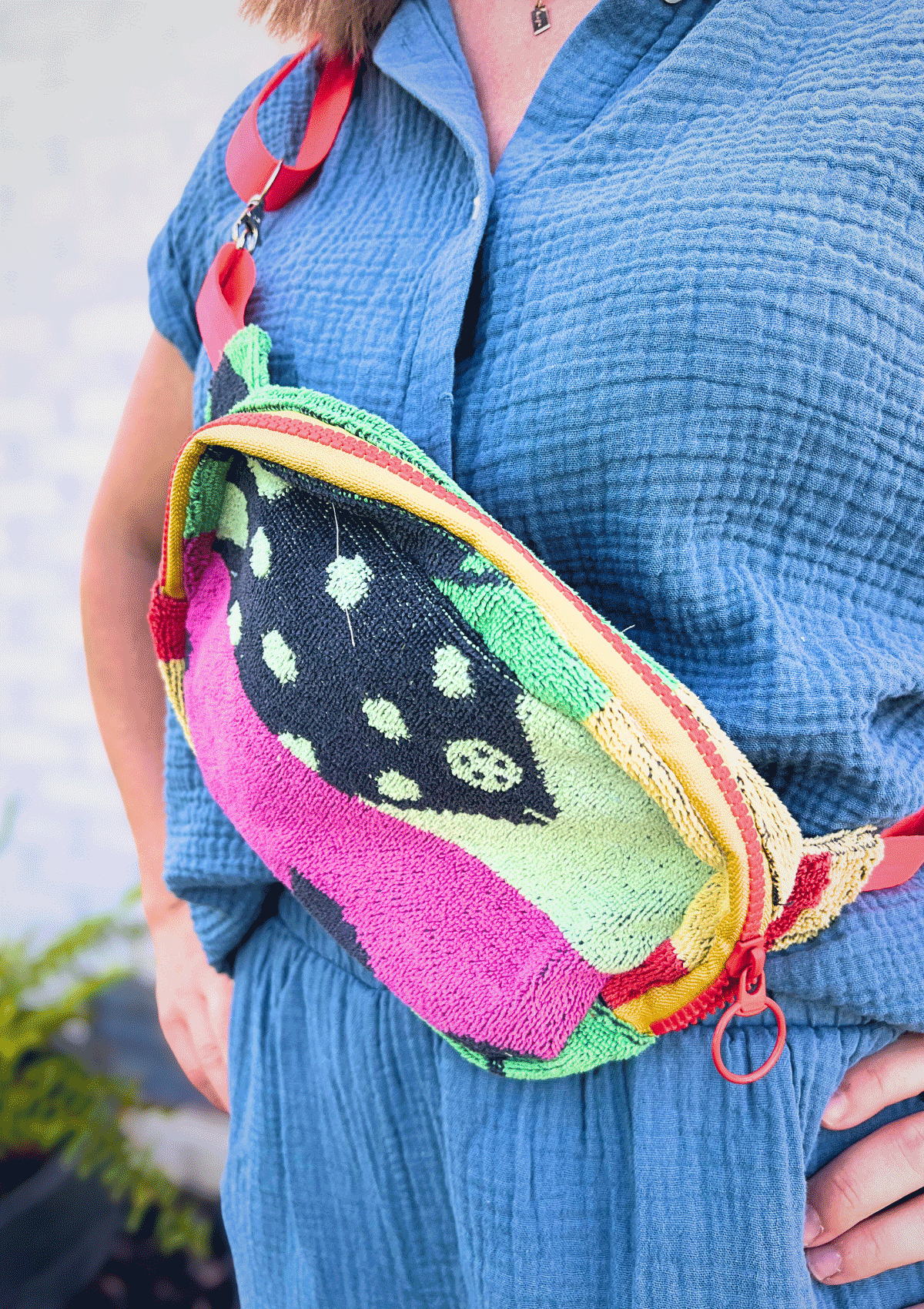 Person wearing a colorful cross body bag upcycled from beach towel, wearing a blue shirt