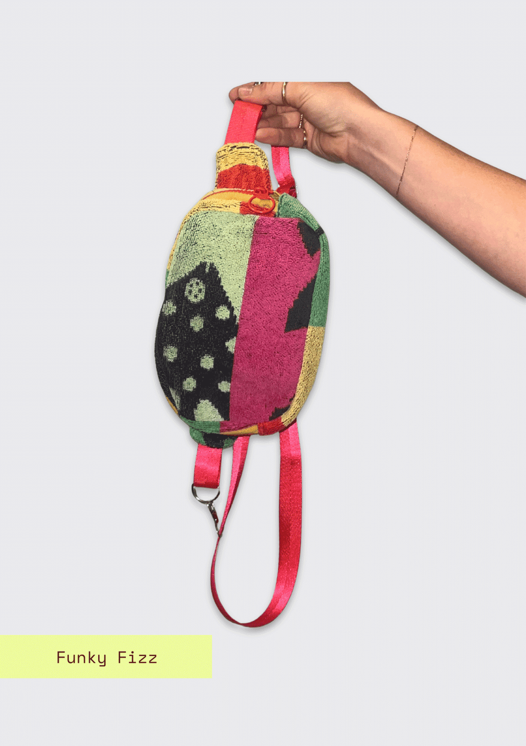 Colorful patterned fanny pack, upcycled from beach towel, held by a hand on a light gray background with 'Funky Fizz' branding.