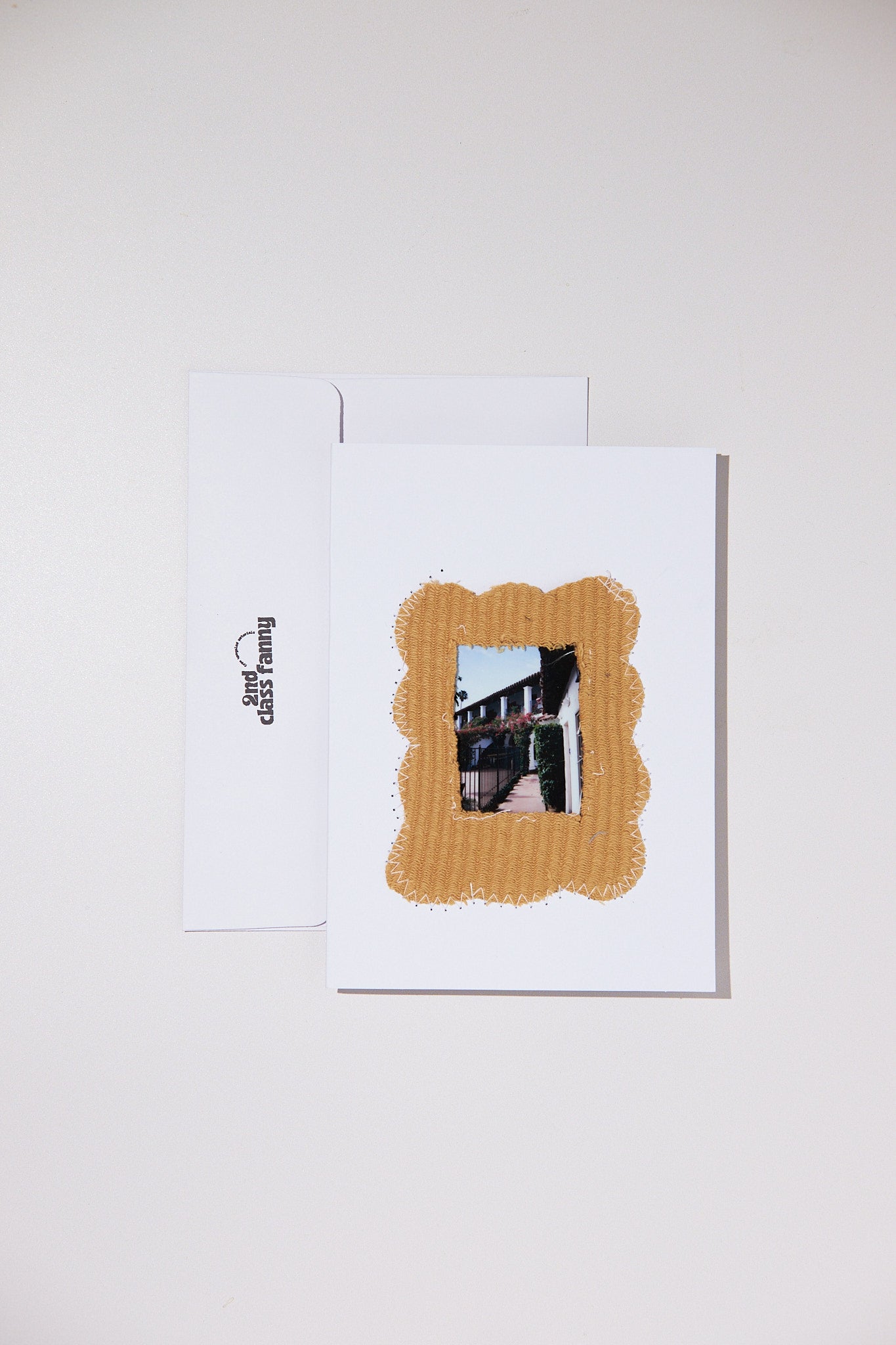 White card with a yellow border upcycled fabric from a sweater featuring a small opening for your own Polaroid on a white background