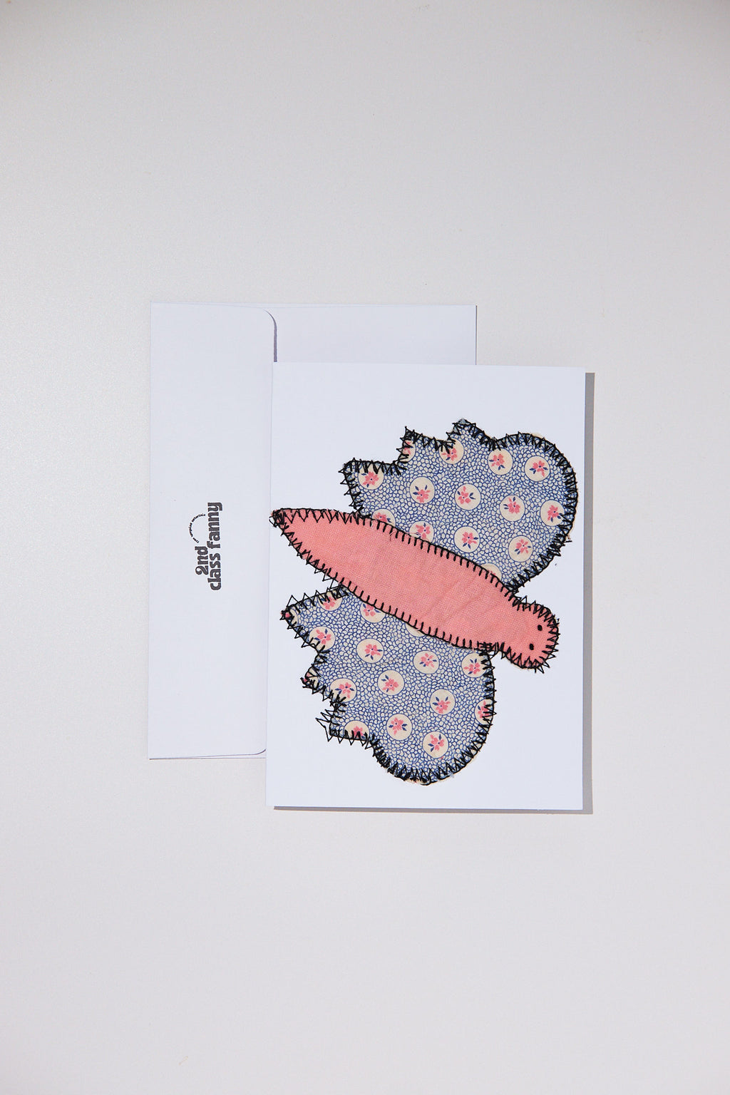 Butterfly-shaped patch with floral pattern on a white card against a light gray background