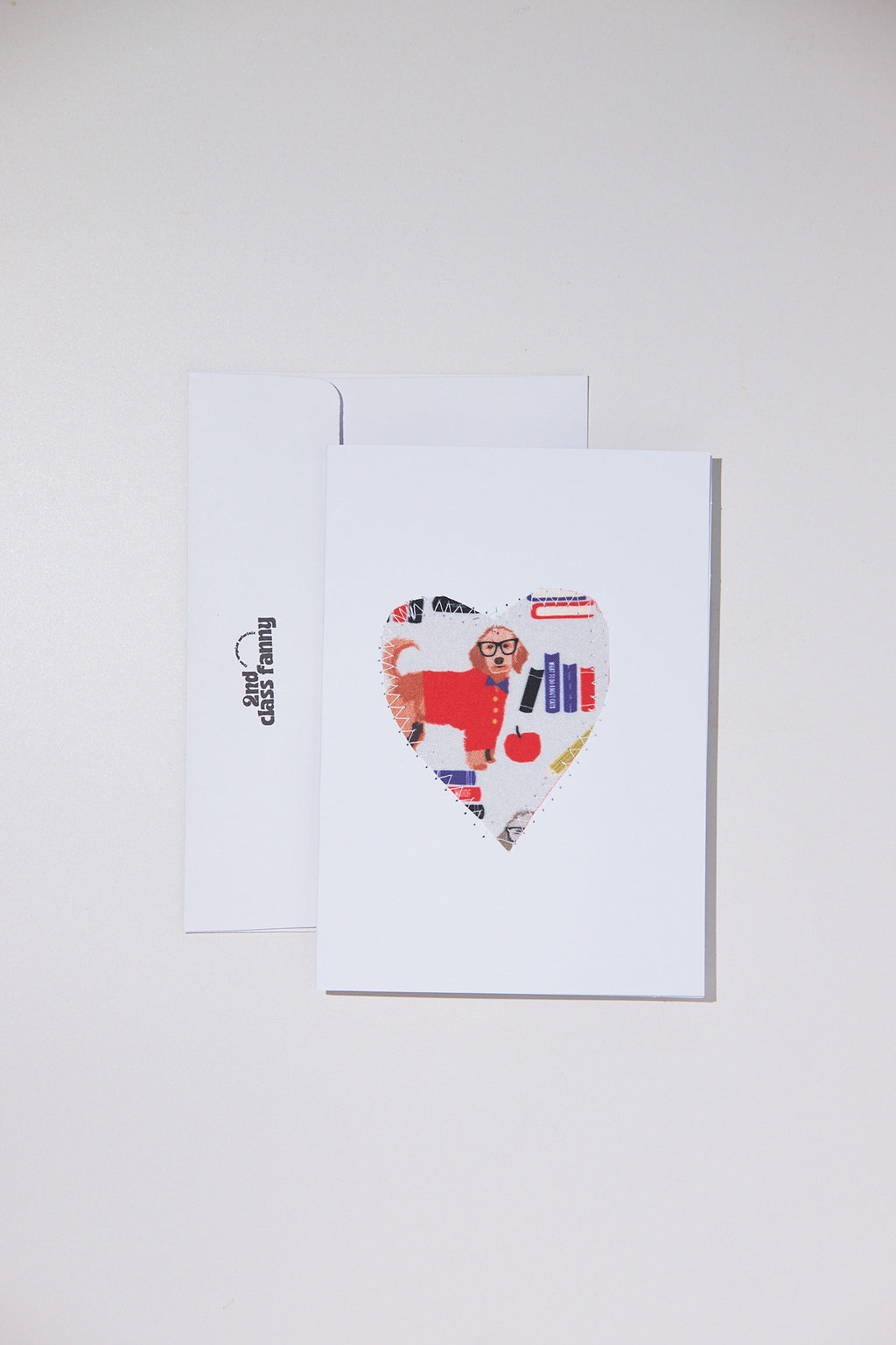 Colorful heart-shaped card with a dog design on a white envelope against a light gray background