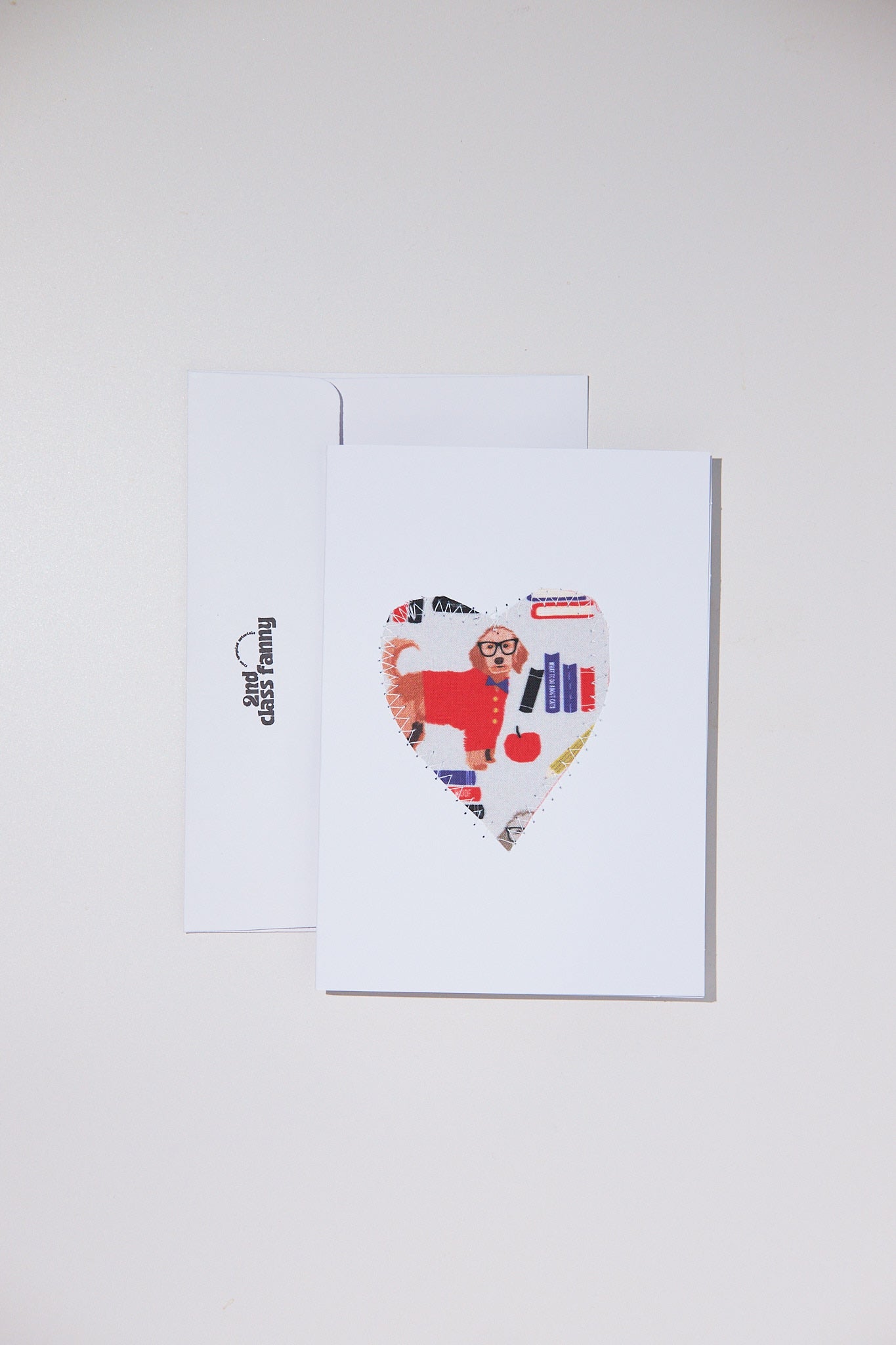 Colorful heart-shaped card with a dog design on a white envelope against a light gray background