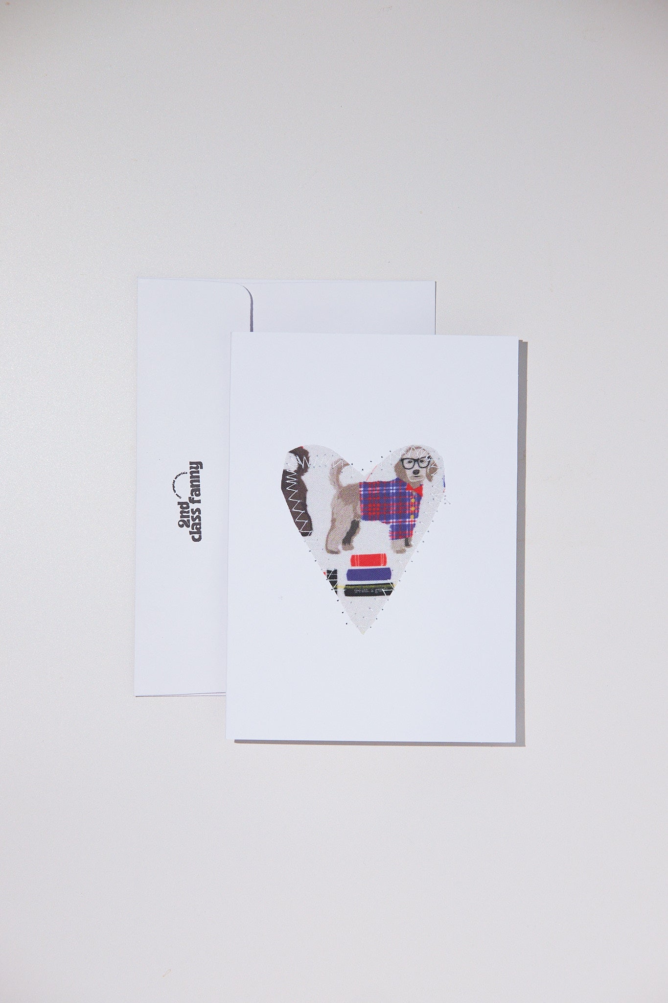 Greeting card with a dog wearing a plaid coat and scarf on a white background