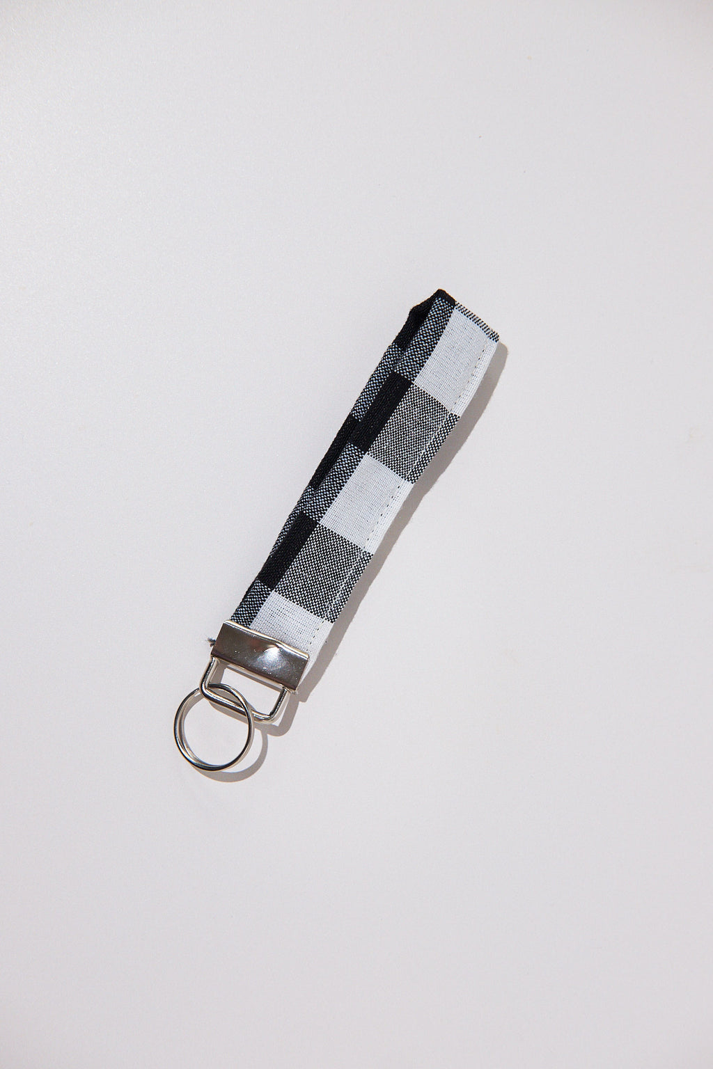 Keychain with a black and white checkered strap  upcycled from curtains on a light gray background