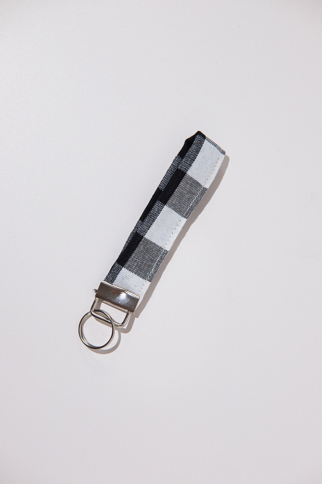 Keychain with a black and white checkered strap  upcycled from curtains on a light gray background