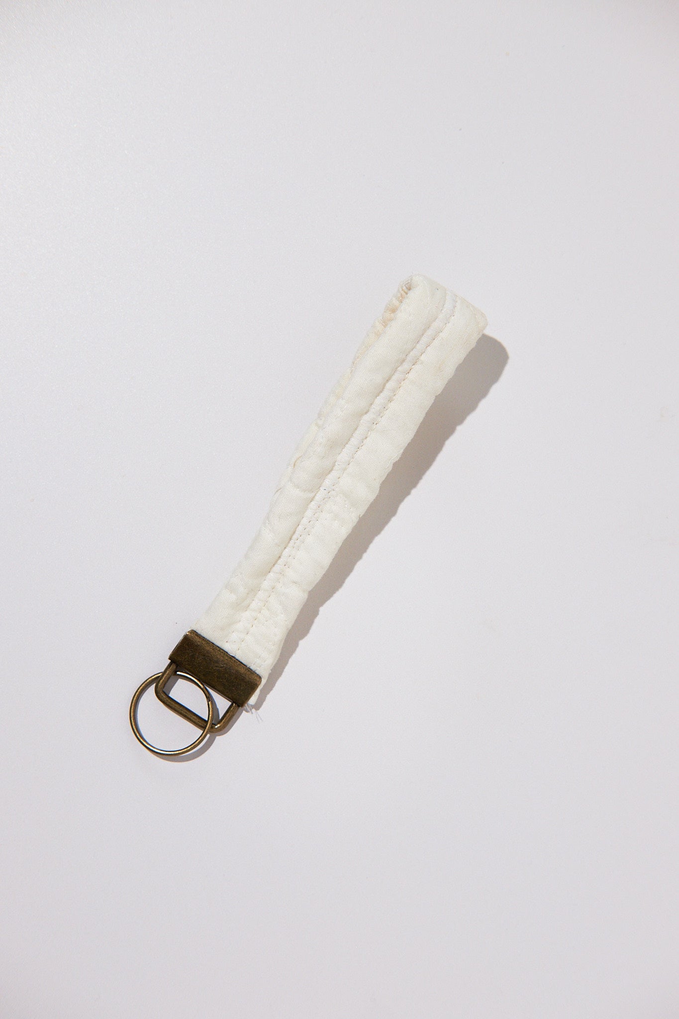 White textured keychain with a metal ring on a light gray background
