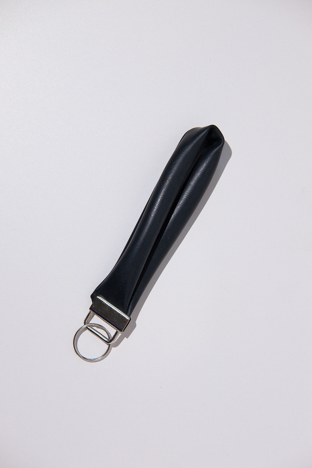 Black keychain upcycled from an inner tube on a white background