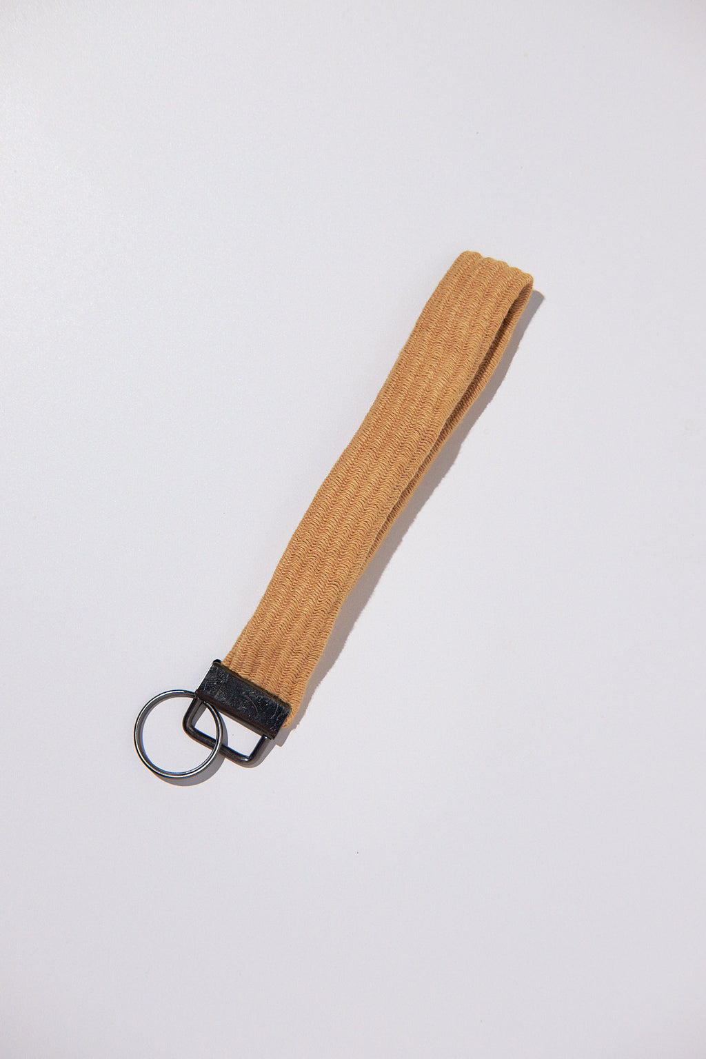 Brown keychain strap upcycled from a sweater with black clip on a white background